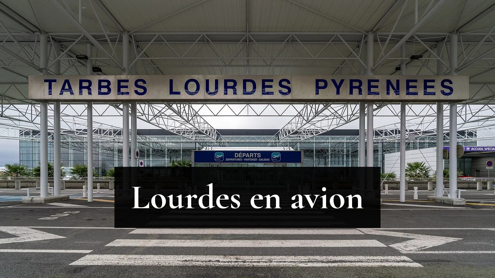 L'entrée de l'aérogare de Tarbes-Lourdes-Pyrénées, sous l'auvent métallique portant l'inscription « Tarbes Lourdes Pyrénées », avec la porte des départs au fond