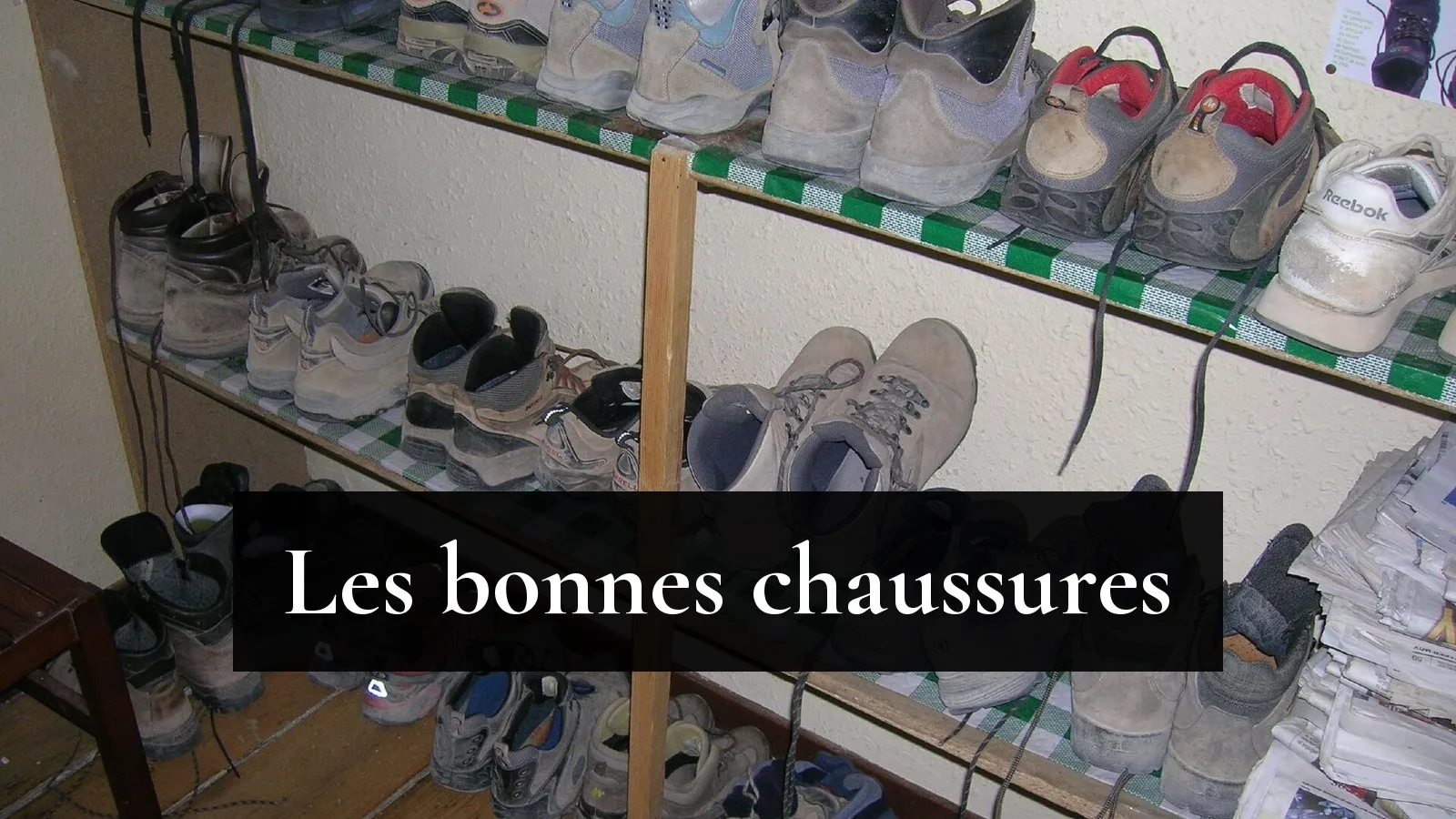 Étagère d'un hébergement de pèlerins garnie de chaussures de marche usées, bottes et baskets, au retour de l'étape