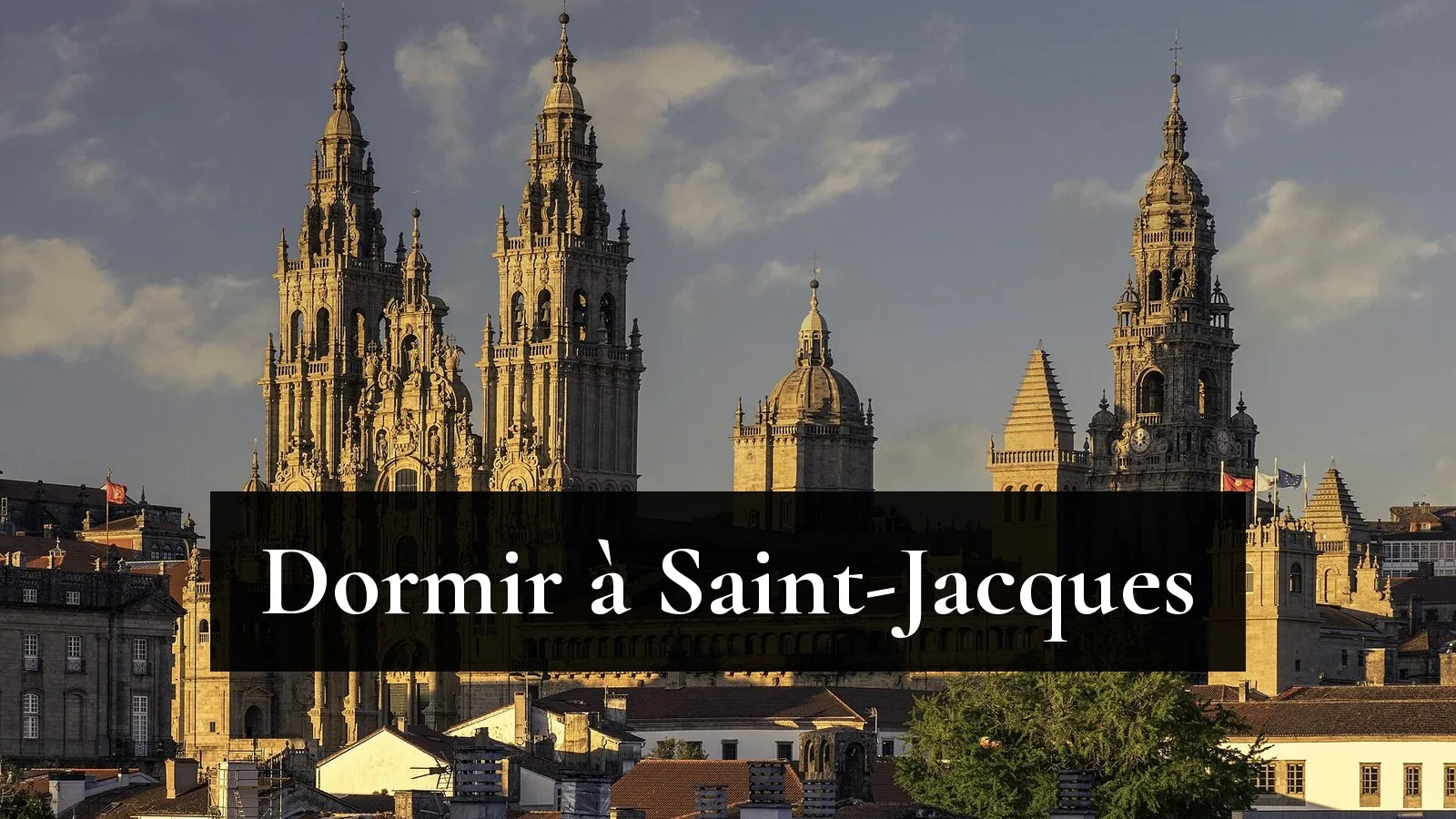 Les tours de la cathédrale de Saint-Jacques-de-Compostelle dorées par le soleil couchant, au-dessus des toits de la vieille ville